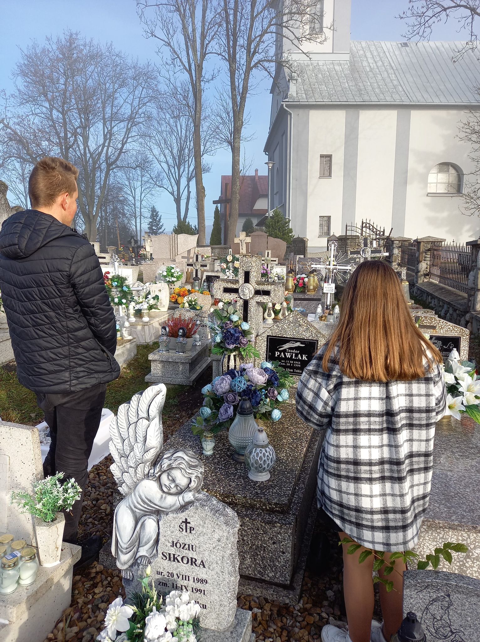 Zdjęcie przedstawia przedstawicieli samorządu uczniowskiego zapalających znicz na grobie Pana Teodora Pawlaka